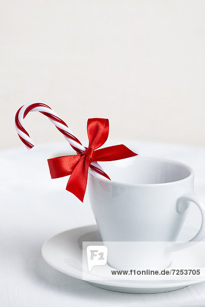 Tasse dekoriert mit Zuckerstange und roter Schleife