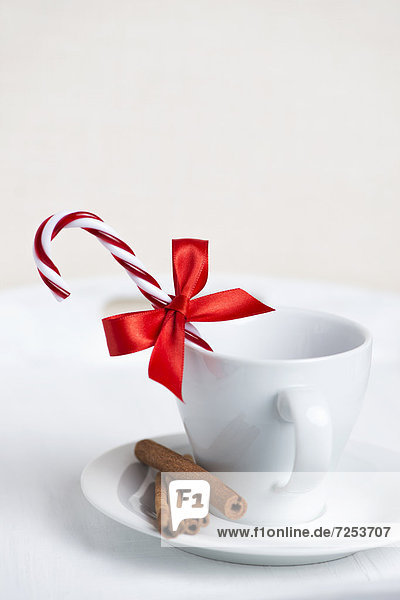 Tasse dekoriert mit Zuckerstange  roten Schleife und Zimtstangen