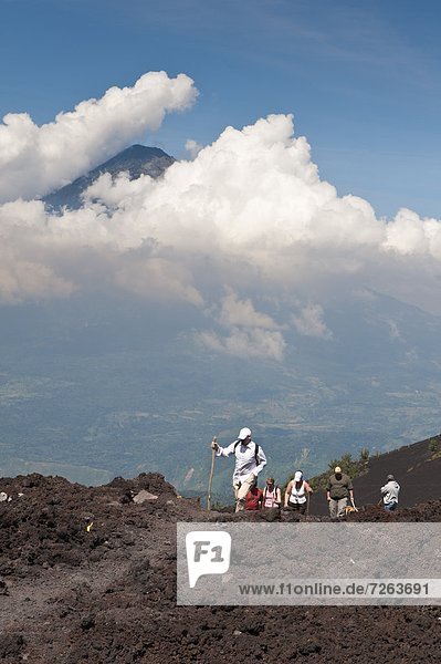 Climbing Pacaya volcano  with Fuego Volcano in distance  Antigua  Guatemala  Central America