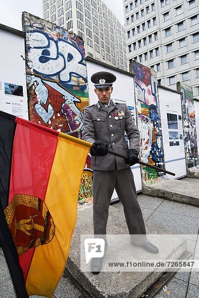 East German guard with former GDR flag in front of remains of the Berlin Wall  Potsdamer Platz  Berlin  Germany  Europe