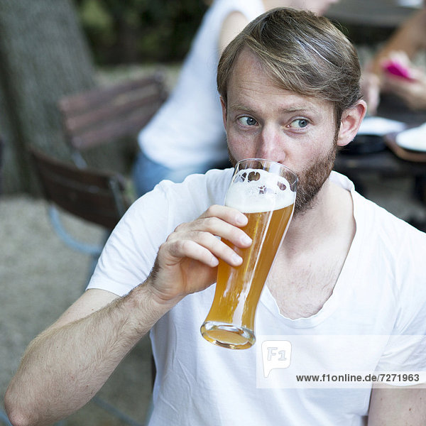 Mann trinkt Weißbier im Biergarten