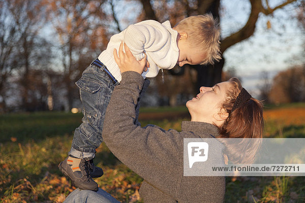 Mutter spielt mit ihrem zweijährigen Sohn im herbstlichen Park