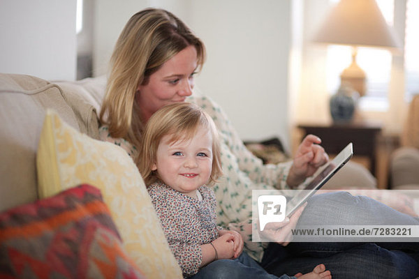 Mutter und Tochter auf Sofa mit digitalem Tablett