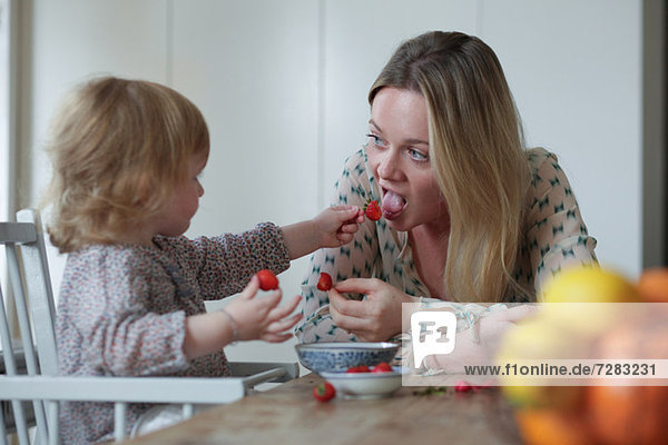 Tochter füttert Mutter Erdbeeren