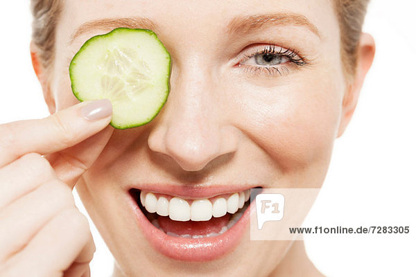 Woman holding a cucumber slice to her eye