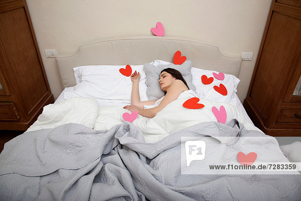 Woman asleep in bed with heart shapes on bedclothes