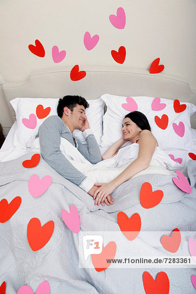 Couple in bed with heart shapes on bedclothes