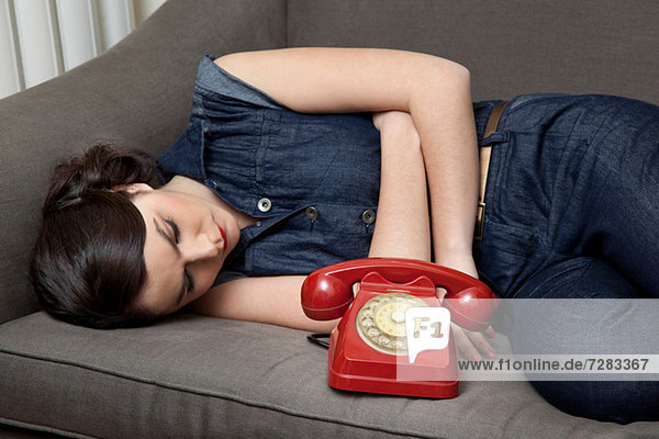 Frau auf Sofa liegend mit Telefon