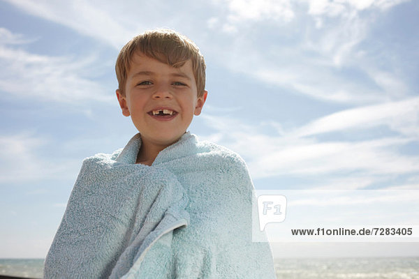 Junge am Meer  in ein Handtuch gewickelt