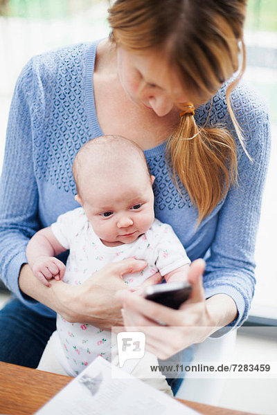 Mother with newborn baby and cell phone