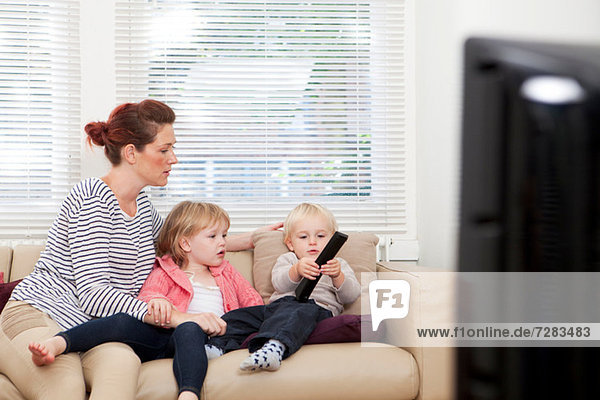 Mother with two children watching television