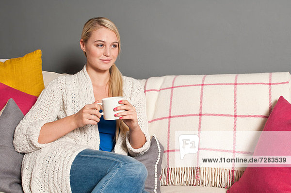 Porträt einer Frau auf einem Sofa mit Tasse