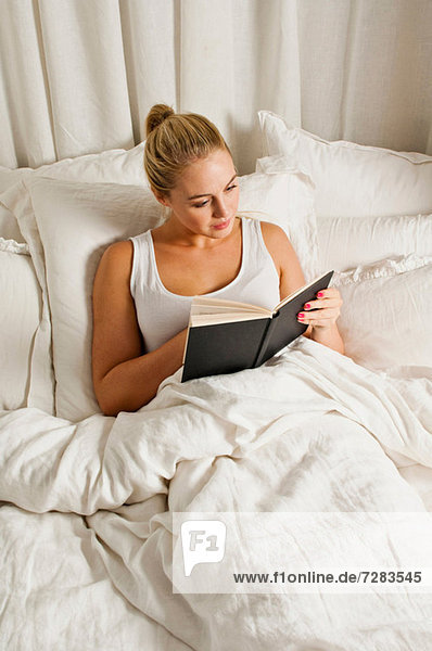 Frau liest Buch im Bett