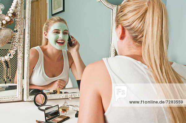 Frau mit Gesichtsmaske am Telefon