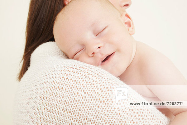 Mutter mit neugeborenem Baby schlafend auf der Schulter