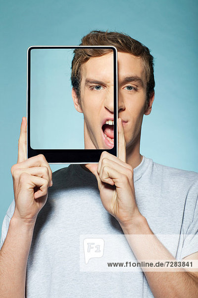 Mann  der sein halbes Gesicht mit einem digitalen Tablett bedeckt.