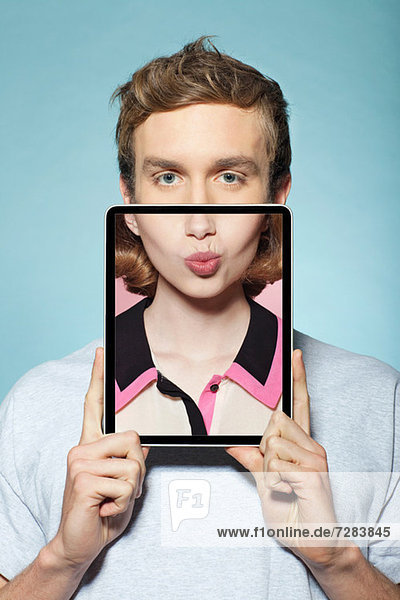 Mann  der sein halbes Gesicht mit digitalen Tabletten bedeckt  mit Frauenmund  Mund