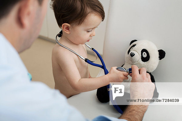 Kleiner Junge und Arzt mit Stethoskop auf Pandaspielzeug