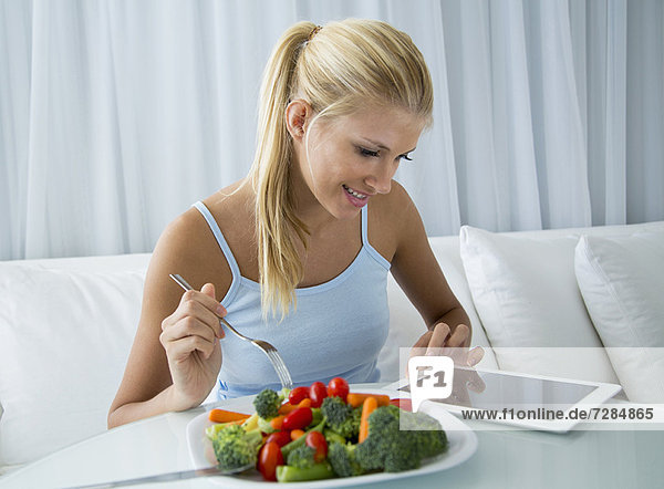 Frau mit Tablet-Computer und Essen