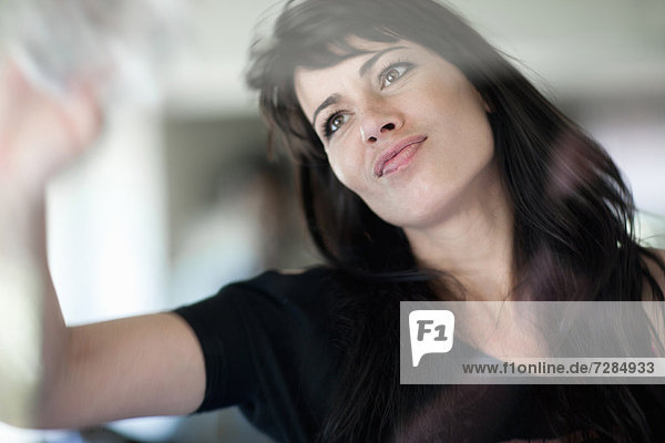 Lächelnde Geschäftsfrau beim Fensterputzen