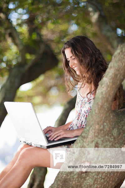 Frau mit Laptop im Baum im Freien