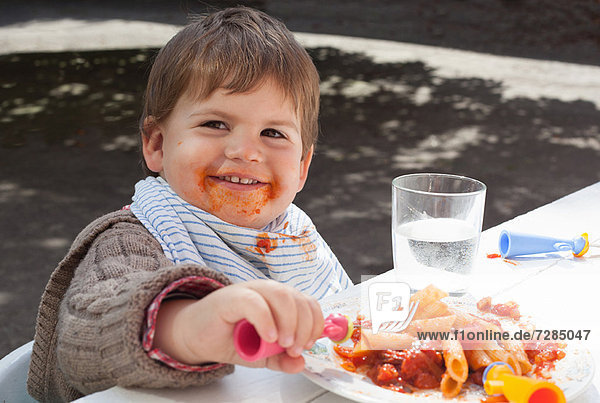 Kleinkind Junge isst Nudeln im Freien