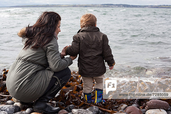 Mother and son playing on rocky beach