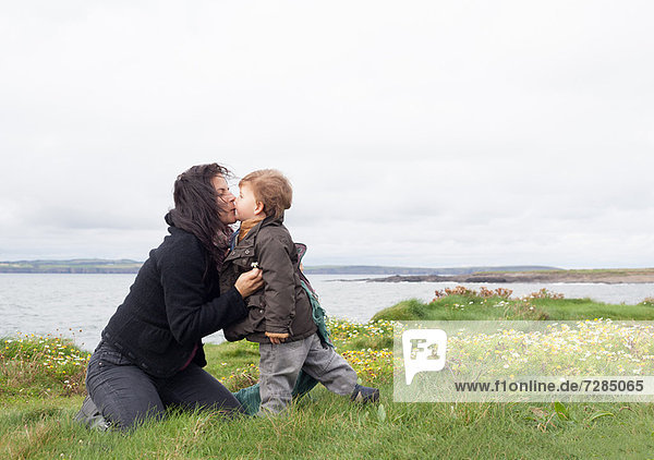 Mutter und Sohn küssen sich im Grasfeld
