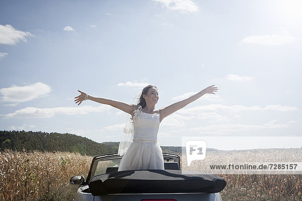 Newlywed bride standing in convertible