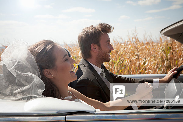 Newlywed couple driving in convertible