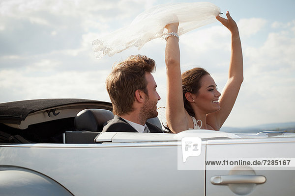 Newlywed couple riding in convertible