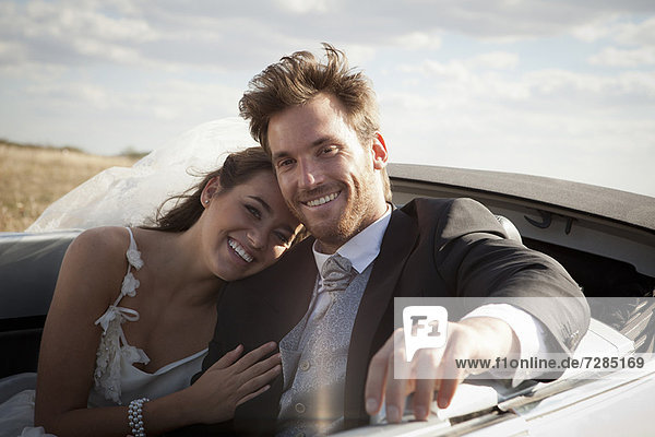 Newlywed couple riding in convertible