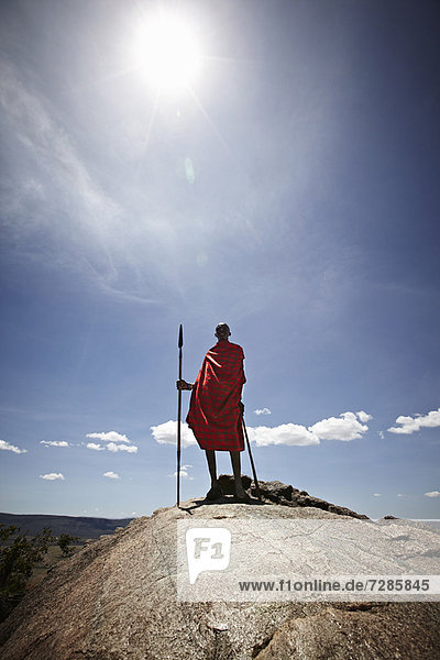 Maasai-Mann auf dem Felsen stehend