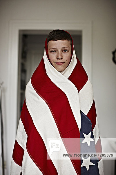 Junge in amerikanische Flagge gehüllt  drinnen