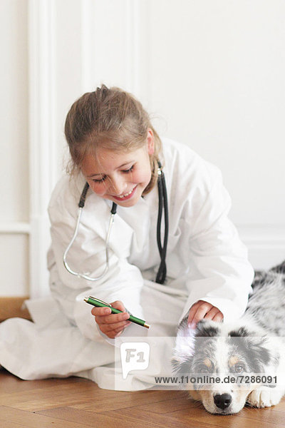 Mädchen spielt Arzt mit Hund