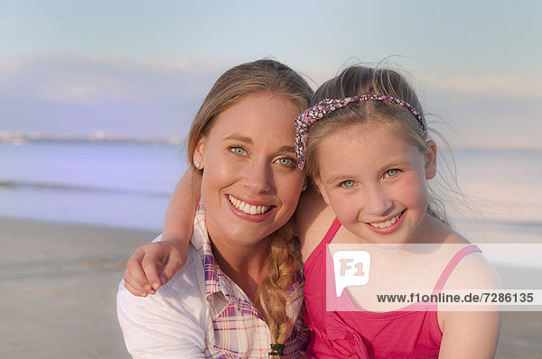 Mutter und Tochter lächeln am Strand