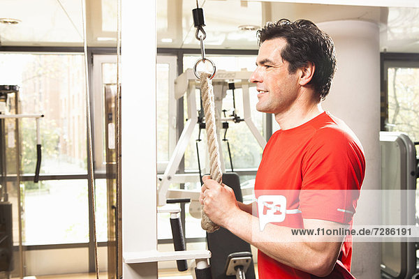 Mann mit Trainingsgeräten im Fitnessstudio