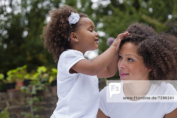 Mädchen beim Spielen mit dem Haar der Mutter im Freien