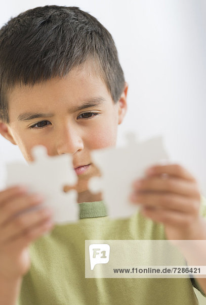 Boy (6-7) holding jigsaw pieces