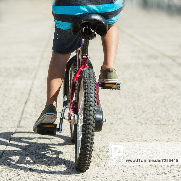 Low section of boy (6-7) riding bicycle