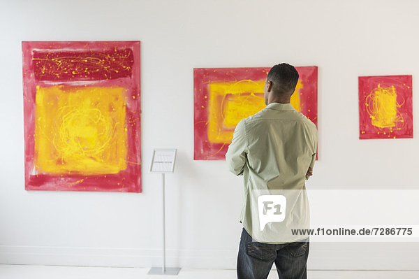 Man watching paintings in modern art gallery