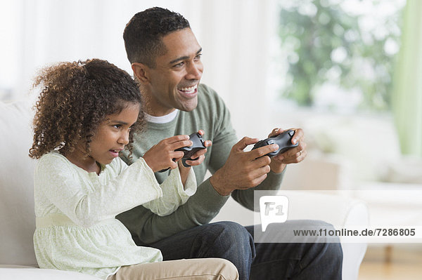 Father and daughter (6-7) playing video game
