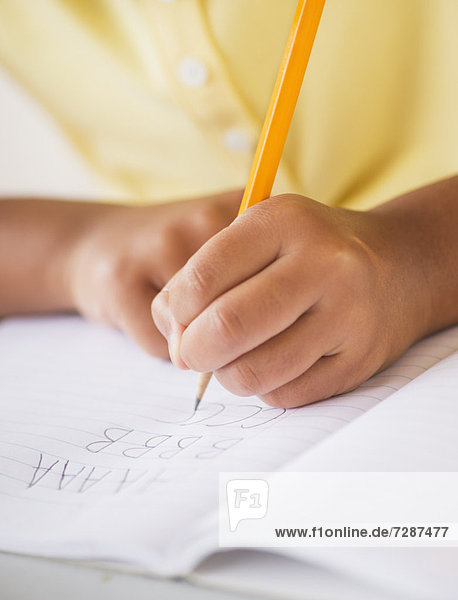 Girl (6-7) doing homework  close-up of hands