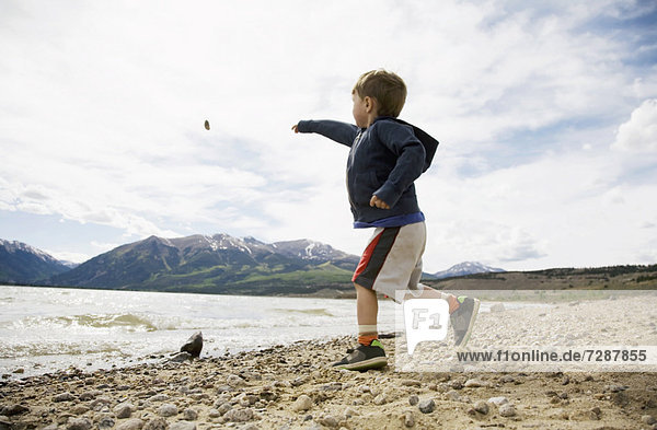 Boy (2-3) throwing rock in lake