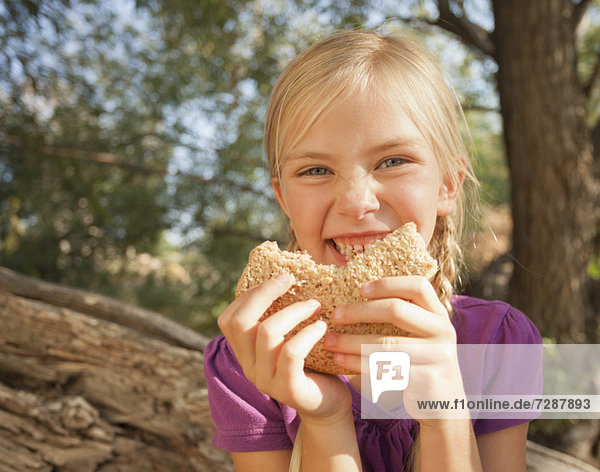 Little girl (4-5) eating peanut butter and jelly sandwich
