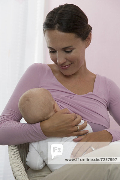 Mother breastfeeding baby daughter (6-11 months)