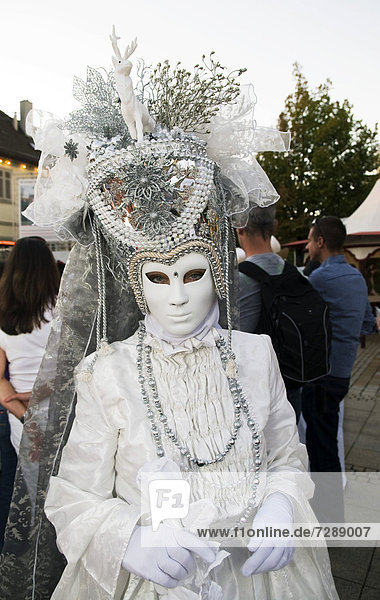 Woman in a white costume with a white mask and a large headdress  Venetian Fair  Ludwigsburg  Baden-Wuerttemberg  Germany  Europe