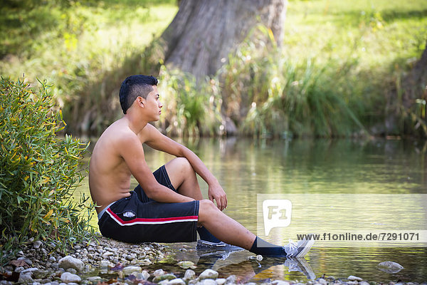 USA  Texas  Teenage boy sitting at Frio River