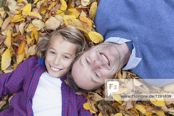Germany  Leipzig  Father and son lying on leaves  smiling