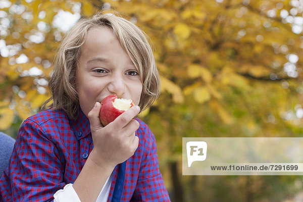 Ein Junge  der einen Apfel isst.